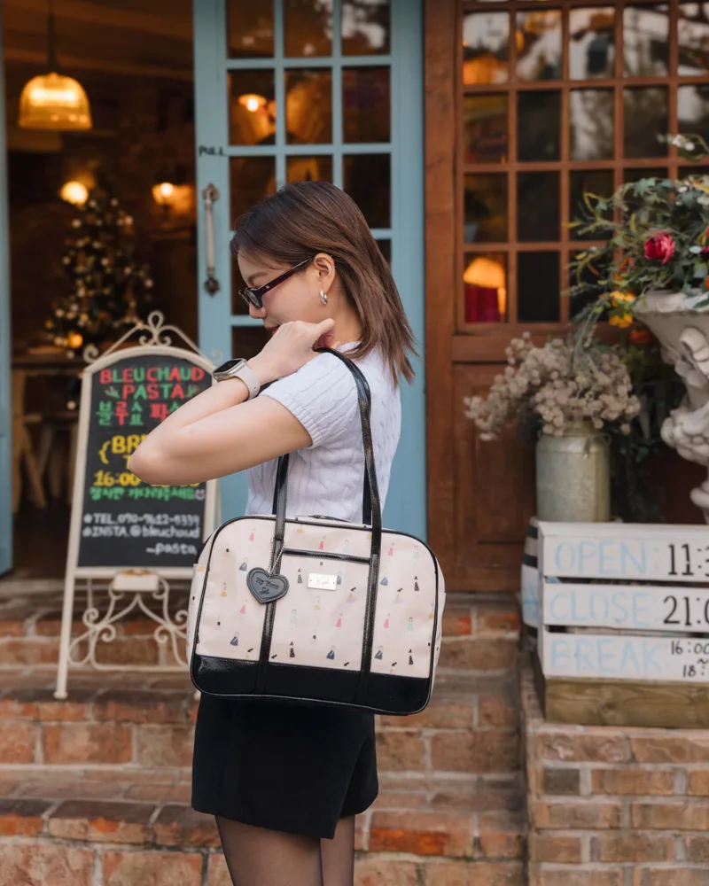 นางแบบสะพายกระเป๋า The Carry Tote ลาย Little Girls เดินออกจากหน้าร้านอาหารยามเย็น