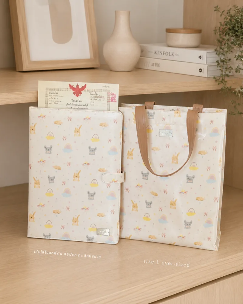 กระเป๋า KEPT ลาย My Sunshine หูหิ้วน้ำตาล — เล่มใส่โฉนดที่ดิน และกระเป๋าถือ L over-sized บนชั้นไม้